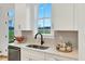 Modern kitchen with stainless steel sink, sleek faucet, white cabinets, and view to private backyard at 1467 Antioch Church Rd, Timberlake, NC 27583