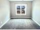 Empty bedroom with grey carpet, grey walls, and a large window at 182 Inverness St, Zebulon, NC 27597
