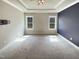 A spacious bedroom with plush carpet, modern ceiling fan, and abundant natural light from two large windows at 182 Inverness St, Zebulon, NC 27597