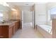Bright bathroom featuring a granite double vanity, soaking tub, and an open doorway to another room at 1922 Pattersons Mill Rd, Durham, NC 27703