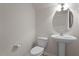 Bathroom with a pedestal sink, toilet, round mirror, and white walls at 2017 Ollivander Dr, Cary, NC 27519