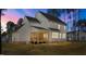 A dusk rear view of the property shows the deck, patio and yard, with lights on inside the house at 25 Arbor Dr, Youngsville, NC 27596