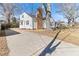 View of a charming white home with a brick chimney and a long, paved driveway on a sunny day at 307 Gordon St, Roxboro, NC 27573