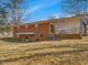 Brick home's rear view highlighting a covered patio and concrete block porch area, with a large lawn at 427 Watson Rd, Efland, NC 27243