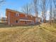 Back of the brick home with a covered patio, showcasing the large yard space and mature trees at 427 Watson Rd, Efland, NC 27243
