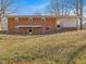 Brick home's back exterior featuring a covered patio and concrete block porch, set on a spacious lawn with mature trees at 427 Watson Rd, Efland, NC 27243