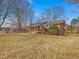 Sprawling brick home with a covered front porch, surrounded by mature trees and expansive lawn, offering serene lakeside views at 427 Watson Rd, Efland, NC 27243
