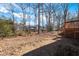 Large, tree-lined backyard featuring a spacious area and a wooden deck at 6312 New Market Way, Raleigh, NC 27615