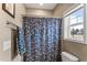 Cozy bathroom with a floral shower curtain, towel rack, and window providing natural light at 6804 Arlington Oaks Trl, Raleigh, NC 27603