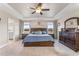Main bedroom with wood accent wall, carpet, tray ceiling with fan and en suite bathroom entrance at 6804 Arlington Oaks Trl, Raleigh, NC 27603