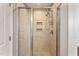 Walk-in shower featuring glass doors, neutral tile, and recessed niche for toiletries in updated bathroom at 6804 Arlington Oaks Trl, Raleigh, NC 27603