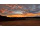 Sunset view from the property showcasing a large backyard with a fence and a tree line in the distance at 6804 Arlington Oaks Trl, Raleigh, NC 27603