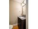 Powder room featuring granite counters, dark wood cabinets, hardwood floors, and a decorative framed mirror at 708 Kenmore Rd, Chapel Hill, NC 27514