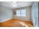Bedroom featuring hardwood floors, gray walls, ceiling fan, and large window that provides natural light at 708 Kenmore Rd, Chapel Hill, NC 27514