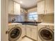 Functional laundry room with white cabinetry, modern washer and dryer, a utility sink, and patterned tile floors at 708 Kenmore Rd, Chapel Hill, NC 27514