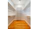 Spacious walk-in closet with hardwood floors and white shelves and rods for clothes storage at 708 Kenmore Rd, Chapel Hill, NC 27514