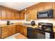 Well-equipped kitchen featuring wooden cabinets and sleek black appliances for culinary enthusiasts at 7925 Brown Bark Pl, Raleigh, NC 27615