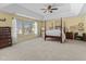 Spacious primary bedroom with a four-poster bed, tray ceiling, large windows, and ample natural light at 80 Ingle View Ct, Burlington, NC 27215