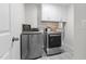 Laundry room with grey side-by-side washer and dryer, upper cabinets, and patterned tile flooring at 978 Gateway Commons Cir, Wake Forest, NC 27587