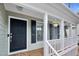 Inviting front porch with black door and shutters, wood flooring, and hanging flower baskets at 107 Fishers Creek Ct, Cary, NC 27513