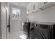Well-lit laundry room featuring modern washer and dryer units, white cabinetry, and marble tile flooring at 112 Rawhide Dr, Louisburg, NC 27549