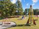 Community playground featuring a rocket-themed climbing structure, swing set, and slide, surrounded by trees at 112 Rawhide Dr, Louisburg, NC 27549