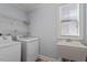 Laundry room with utility sink, shelving, and modern washer and dryer at 1135 Rosepine Dr, Cary, NC 27519