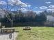 Large backyard with a fire pit, a wooden bench with storage, and a mix of grass and rock areas at 200 Lindell Dr, Apex, NC 27539