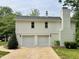 Two-car garage with a gravel driveway, adjacent to a brick chimney and surrounded by lush trees at 2115 Port Royal Rd, Raleigh, NC 27609