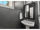 Stylish powder room with pedestal sink, dark gray walls and modern mirror at 2128 Arborwood Dr, Durham, NC 27705