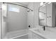 Modern bathroom with a white tub, square tiles, black fixtures, and natural light at 228 Woodsborough Pl, Raleigh, NC 27601