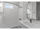 Modern bathroom featuring a shower-tub combo with white tiling, and a black framed mirror at 228 Woodsborough Pl, Raleigh, NC 27601
