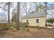 View of the back exterior, with well-kept yellow siding and mature trees offering shade and privacy at 2618 Elgin St, Durham, NC 27704