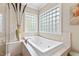 Bathroom featuring a soaking tub with tile surround, glass block window, and tiled walls at 2920 Claremont Rd, Raleigh, NC 27608