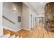 Elegant hallway featuring hardwood floors, stone accent wall, and staircase with wooden handrail at 2920 Claremont Rd, Raleigh, NC 27608