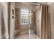 Walk-in shower with glass doors, travertine walls, tile flooring and window block at 2920 Claremont Rd, Raleigh, NC 27608