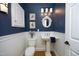 Stylish powder room with navy blue walls, white wainscoting, and a classic pedestal sink at 3937 Bentley Brook Dr, Raleigh, NC 27612