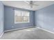 This comfortable bedroom features soft carpet, ceiling fan, and a large window offering plenty of natural light at 401 Acorn Falls Ct, Holly Springs, NC 27540