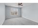 Bright bedroom features soft carpet, ceiling fan, and a large window offering plenty of natural light at 401 Acorn Falls Ct, Holly Springs, NC 27540