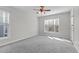 This bedroom has lots of natural light, neutral paint and carpet, and a ceiling fan at 401 Acorn Falls Ct, Holly Springs, NC 27540