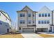 Three-story home with light gray siding, a two-car garage, and a concrete driveway at 4724 Cypress Tree Ln, Raleigh, NC 27612