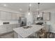 Bright kitchen showcasing gray cabinetry, a central island with sink, and stainless steel appliances at 517 Providence Springs Ln, Fuquay Varina, NC 27526