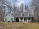 Charming light green home with a welcoming front porch and dormer windows surrounded by a wooded lot at 613 Hamecon Place, Cedar Grove, NC 27231