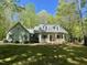 Charming home with a covered front porch, American flag, and mature landscaping on a sunny day at 613 Hamecon Place, Cedar Grove, NC 27231