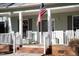 Close-up of the porch with rocking chairs, front door and sidelights, and an American flag at 613 Hamecon Place, Cedar Grove, NC 27231