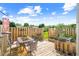 Inviting back deck featuring an outdoor dining set and a charming garden with flowers on a sunny day at 622 Village Lake Drive, Mebane, NC 27302