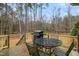 A wood back deck is shown with a grill, dining table and chairs overlooking the fenced backyard at 7100 Winter Pond Way, Fuquay Varina, NC 27526