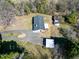 An aerial view shows a brick ranch home and outbuildings surrounded by woods and a lawn at 8604 N Roxboro St, Bahama, NC 27503