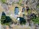 An aerial view of a house with an asphalt roof, a large yard, and several outbuildings surrounded by many trees at 8604 N Roxboro St, Bahama, NC 27503