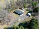 Overhead shot of a brick house featuring a dark roof, curved driveway, and various outbuildings at 8604 N Roxboro St, Bahama, NC 27503